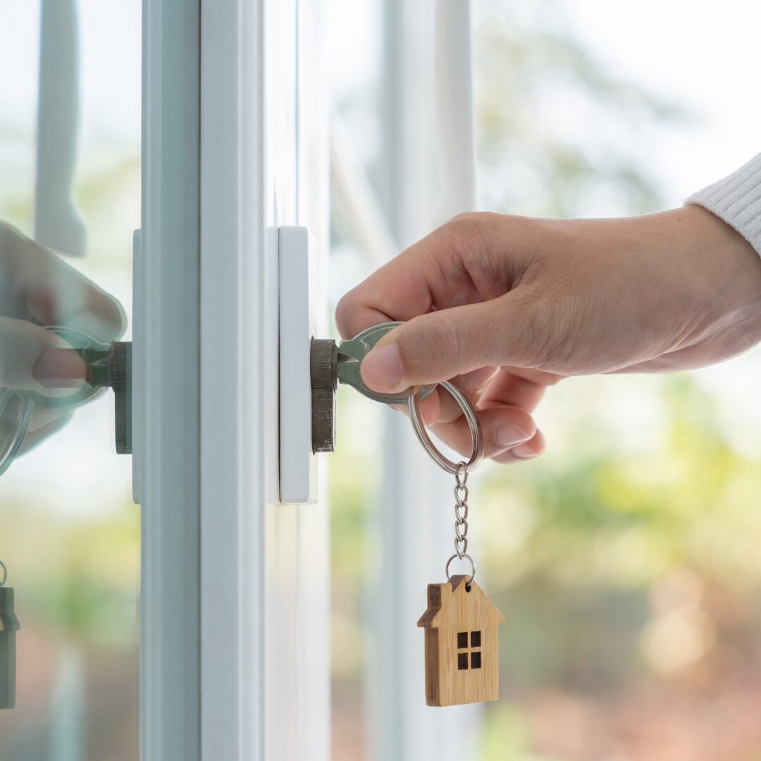 person opening a door with a key and house keychain